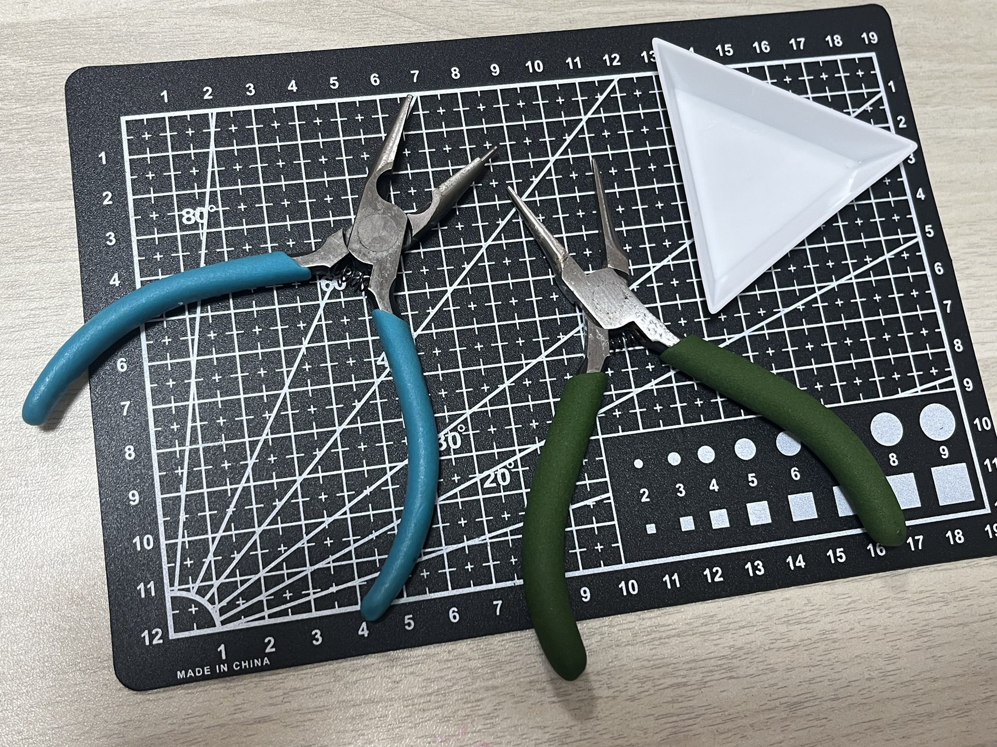 丸カンの開け閉めに使う平ヤットコ2本とカッティングマット